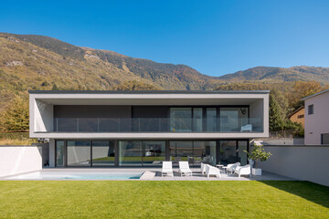 Front view modern house with two floors, pool two deck chairs and a small lounge with white...