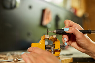 Woman using power working grinder machine, female hand grinds a metal nuts