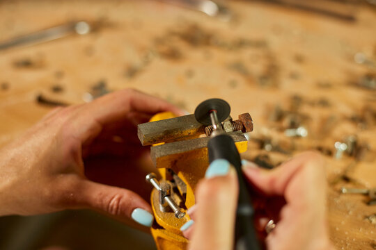 Woman using power working grinder machine, female hand grinds a metal nuts - Powered by Adobe
