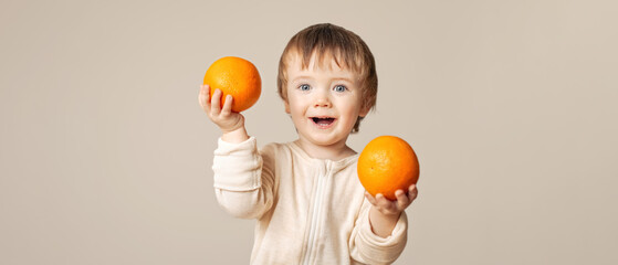 a joyful, smiling baby, a child holding oranges, a banner, a light beige background