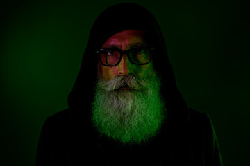 Photo of clever mystic senior guy wear black hoodie arms eyewear isolated dark green color background