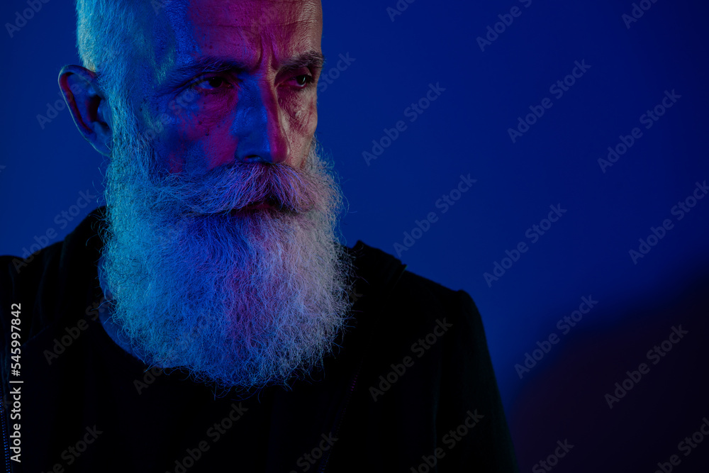 Wall mural Photo of groomed masculine senior guy wear black hoodie looking empty space isolated dark blue color background