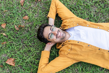 Cheerful ethnic man lying on grass