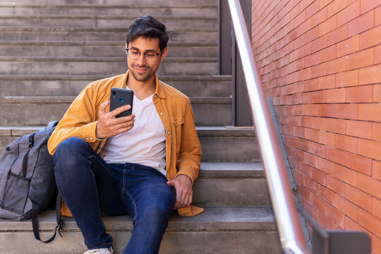 Concentrated man in casual outfit using smartphone on stairs