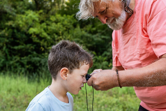 Man holding pocket monocular while kid looking at insect
