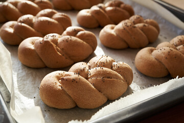 Homemade braided bread buns made from whole grain spelt flour on a baking sheet