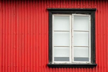 Fototapeta na wymiar Window on a red painted wall, colorful house, architecture detail in Reykjavik, Iceland