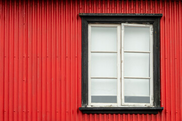 Window on a red painted wall, colorful house, architecture detail in Reykjavik, Iceland