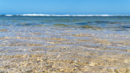 Closeup of sea waves washing the sandy beach on a sunny day
