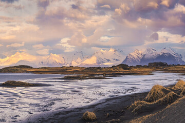 Snowy mountains and black sand beach on cloudy day