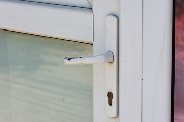 Worn handle on a white plastic indoor door at the entrance of a room