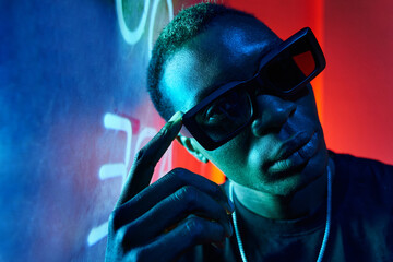 Cool black man in fashionable sunglasses in neon light