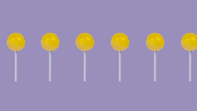 trendy food animation of a lot of yellow fruity lollipops on a lilac background