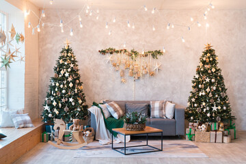 Interior of modern studio living room with comfortable sofa decorated with Christmas trees and gifts.