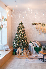 Interior of modern studio living room with comfortable sofa decorated with Christmas trees and gifts.