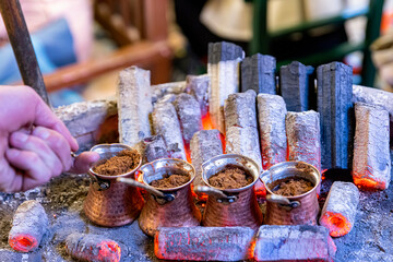 Turkish coffee cooked on embers. Street vendor cooks Turkish coffee on embers. Traditional pottery...