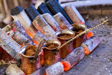 Turkish coffee cooked on embers. Street vendor cooks Turkish coffee on embers. Traditional pottery...