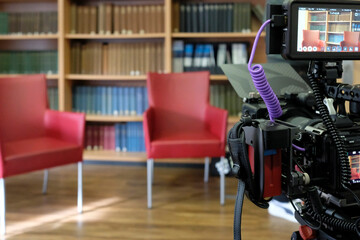 Two empty chairs in a TV studio with book panel in the background and camera in the foreground