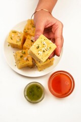 Closeup of a female hand holding Dhokla gujurati food with ketchup beside it