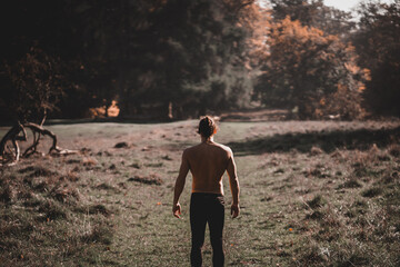 Adult man with ponytail with his back turned looking at the forest in Denmark