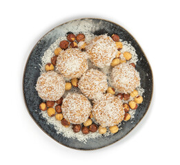 homemade coconut candies with almonds inside, sprinkled with coconut chips, lying on a round plate of dark blue color, decorated with hazelnuts isolate