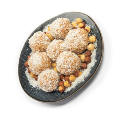 homemade coconut candies with almonds inside, sprinkled with coconut chips, lying on a round plate of dark blue color, decorated with hazelnuts isolate