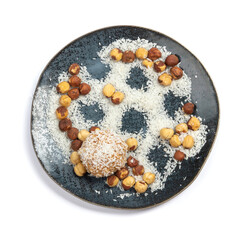 homemade coconut candies with almonds inside, sprinkled with coconut chips, lying on a round plate of dark blue color, decorated with hazelnuts isolate