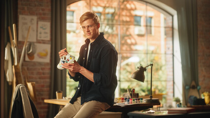 Handsome Teenage Male Designer Standing and Drawing New Creative Sneakers at Home Living Room, Looking at Camera. Artist is Customising Hype Shoes by Adding Own Design. Fashion Project Concept.