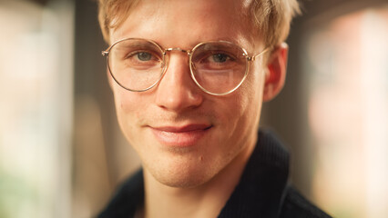 Close-up Portrait of Handsome Blonde Man in Glasses, Looking at the Camera, Smiling. Thoughtful, Attractive Teen Male Sincerely Looking at You. Human Emotions and Stylish People Concept.