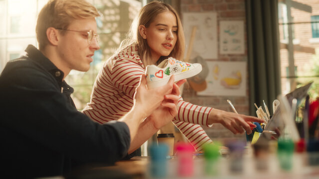 Team of Teenage Fashion Designers Analysing and Discussing Concept of Custom Made Shoes. Smiling Woman Shares Her Ideas With Man. Young Promising Sneaker Artists Collaboration. - Powered by Adobe