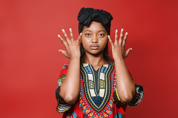 Young African American girl with turban looks seriously at the camera while showing her hands. She...