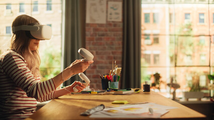 Blonde Woman Wearing 3D VR Headset And Using Modern Controllers in Loft Apartment. Female Designer Working in Futuristic Application. New Technologies and Augmented Reality Concept.