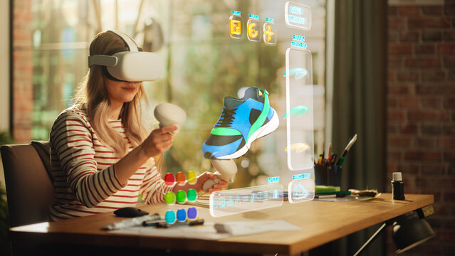 Talented Female Shoes Designer Wearing Virtual Reality Headset and Using Controllers to Design a Fashionable Sneaker in Augmented Reality Software. Woman Working on Digital Footwear at Home.