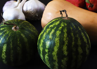 Little watermelons. Dwarf ripe watermelon on the background of other vegetables. Shallow depth of field