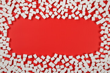 Frame made from sugar cubes on red background with a copy space