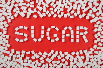 Sugar word and a frame made from sugar cubes on red background