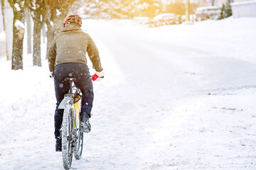 Cyclist rides on snow and snowdrifts in city during blizzard. Man in warm clothes wearing...