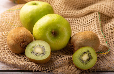 Green apple and kiwi, green apples and kiwi fruit laid on rustic wood with rustic fabric, selective focus