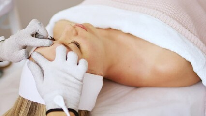 Beautician cosmetologist makes a procedure on the face with microcurrent therapy gloves. Hardware cosmetology in clinic salon for client.	