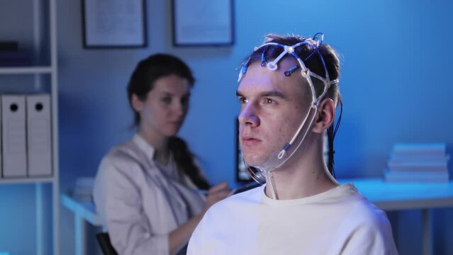 EEG topographer for examining brain, doctor making electrogram of scalp activity. Researching of brain work, man riding bicycle in electroencephalography headset. Rehabilitation after damage in sport.