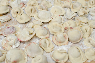 Process of making homemade raw pastry dumplings with meat filling on a wooden Board. Pelmeni. A traditional dish of Russian cuisine. Selective focus