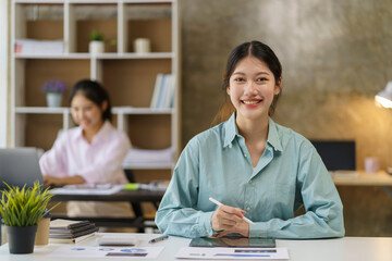 Bright and beautiful young Asian business woman happily at the office to come up with new ideas to work using a tablet smiling.