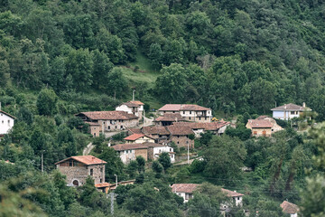 Fototapeta na wymiar small quiet village with lampposts and old stone houses and brown roofs in the middle of the road next to the forest, ruta del cares asturias, spain