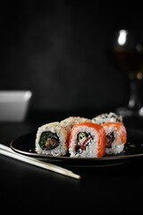 Sushi on a plate, dark background.