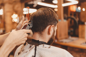 Barbershop concept, vintage color. Closeup man haircut, master does hair styling in barber shop back view