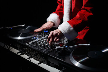 Disc jockey for Christmas party. DJ wearing traditional red Santa Claus costume plays music on...
