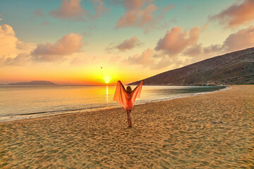 Young woman looking the sunrise from Agia Theodoti beach in Ios, Greece
