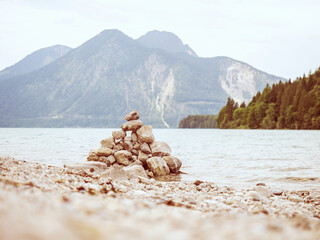 Lake shore. Balanced stones stack. Near Alps peak