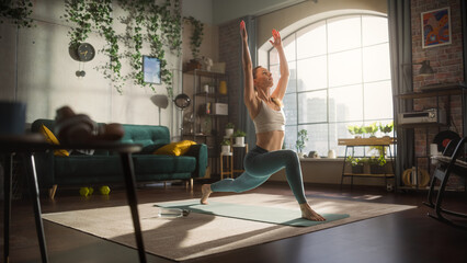 Portrait of a Happy Fit Young Woman Doing Stretching and Core Strengthening Yoga Exercises During Morning Workout at Home in Sunny Apartment. Healthy Lifestyle, Fitness, Wellbeing and Mindfulness.