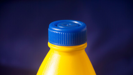 Botella de plástico amarillo con tapón azul de producto de limpieza - obrazy, fototapety, plakaty